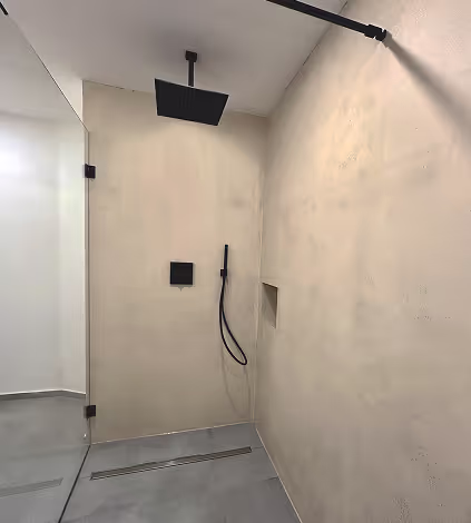 Moderne Dusche mit schwarzer Regenbrause, Handbrause und beige gefliestem Wanddesign.