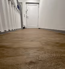 Flur mit Holzfußboden, weißen Wänden und einer weißen Tür am Ende des Korridors.