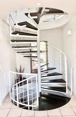 Weiße Wendeltreppe mit schwarzen Stufen in modern gestaltetem Innenraum.